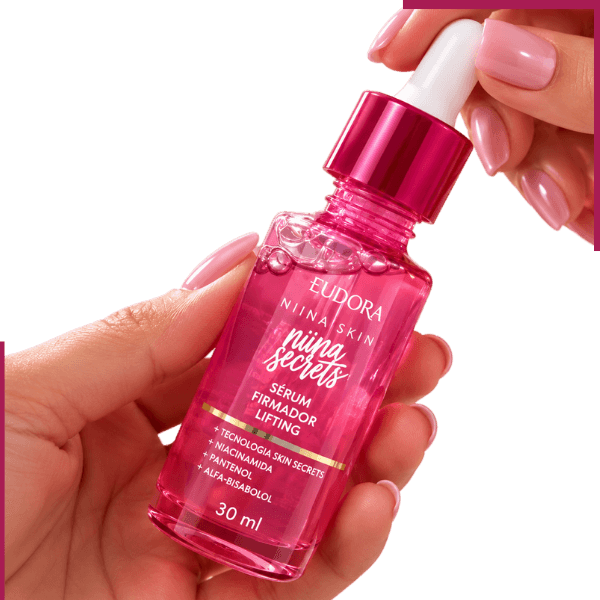 Sérum Firmador Eudora Niina Secrets Skin 30ml com niacinamida e pantenol, apresentado em mãos elegantes para cuidados com a aparência das rugas.
